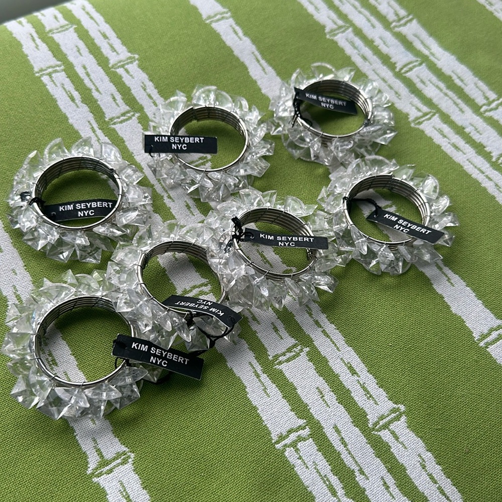 KIM SEYBERT NAPKIN RINGS - set of 7, clear lucite crystals w metal ring. Tag on.